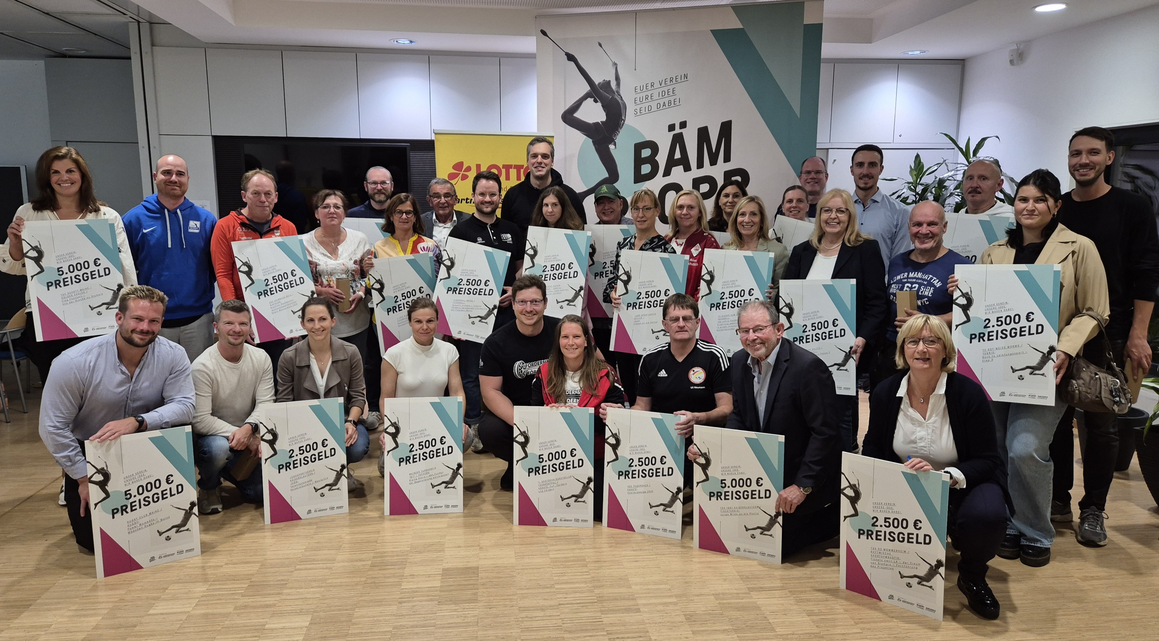 Gruppenfoto bei der BÄM-Award Preisverleihung mit Gewinnern und Preisgeldtafeln