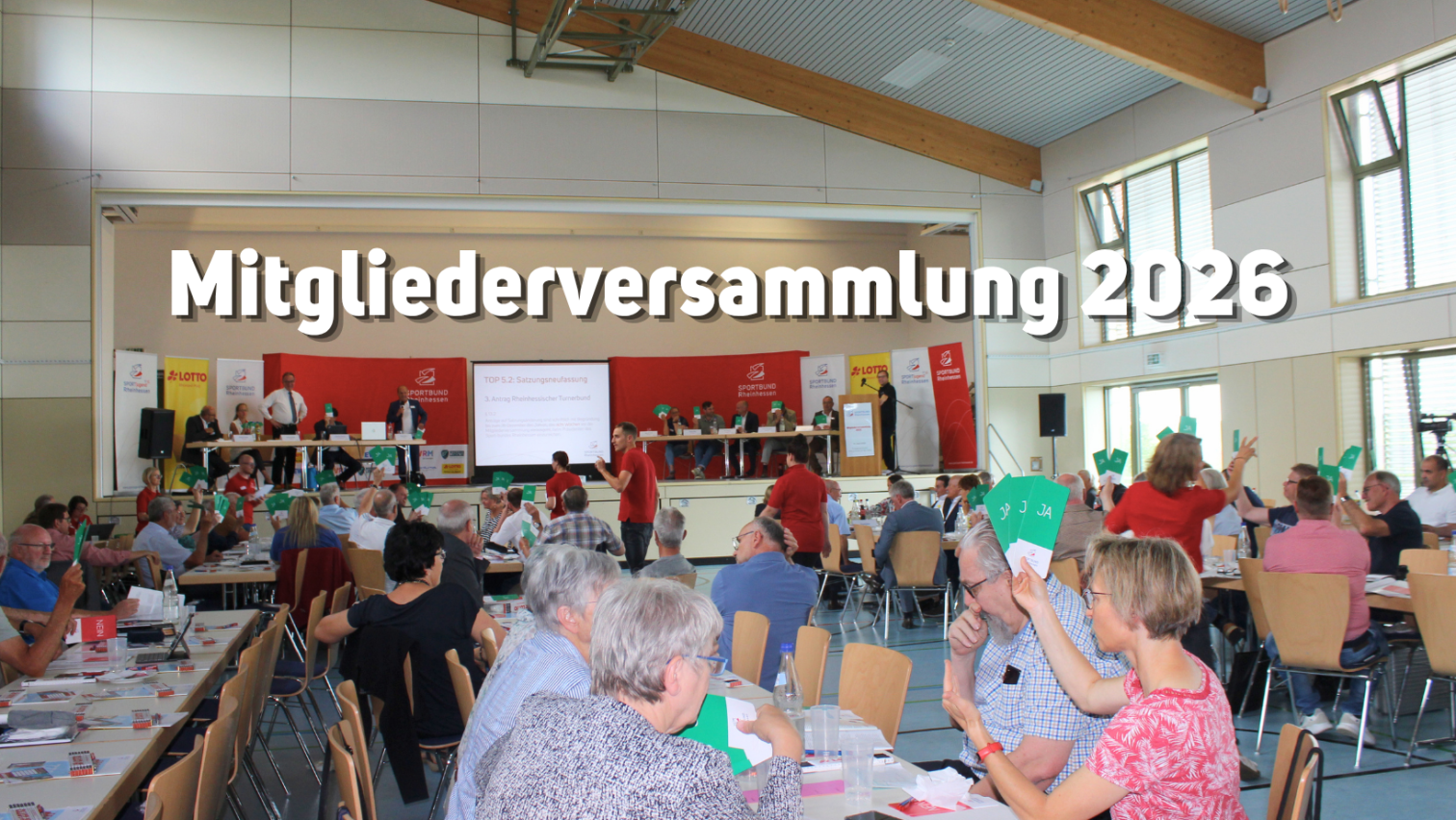 Mitgliederversammlung in einer Halle mit Abstimmungskarten und Podium