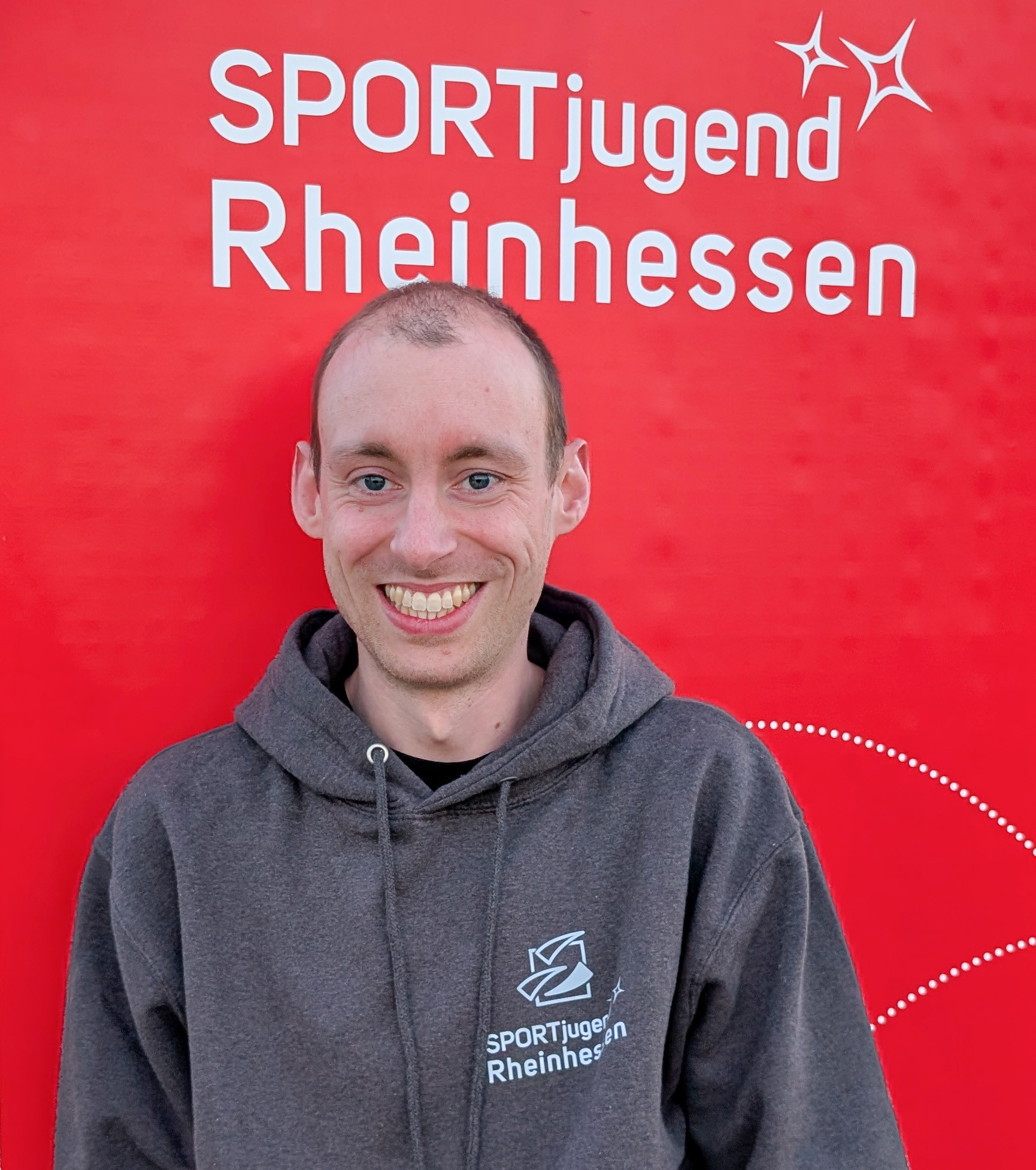 Tobias von der SPORTjugend Rheinhessen vor rotem Hintergrund, aufgenommen am 22.04.2026