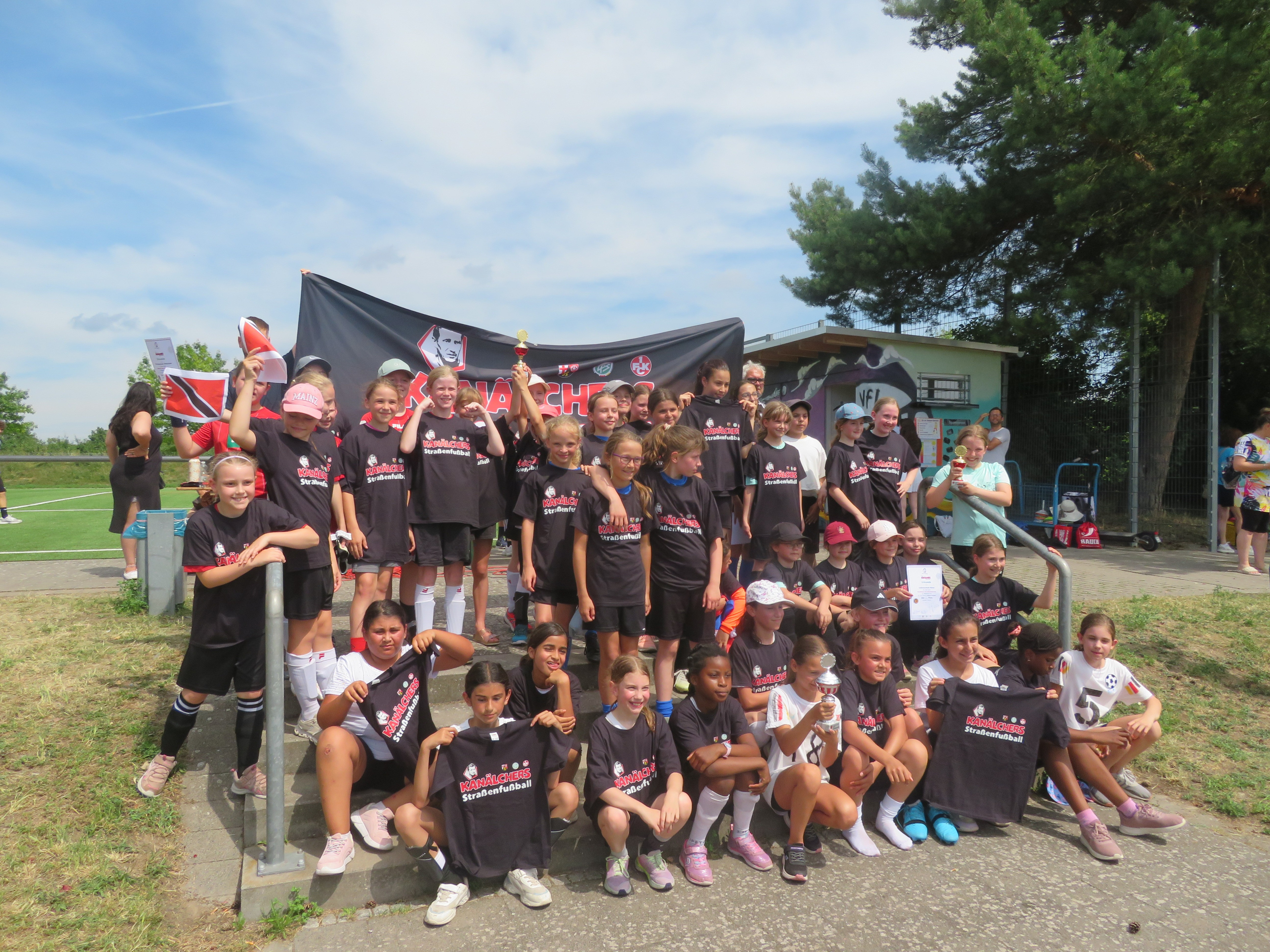 Gruppenfoto von Mädchen-Fußballmannschaft beim Straßenschach-Event mit Pokal und Urkunde