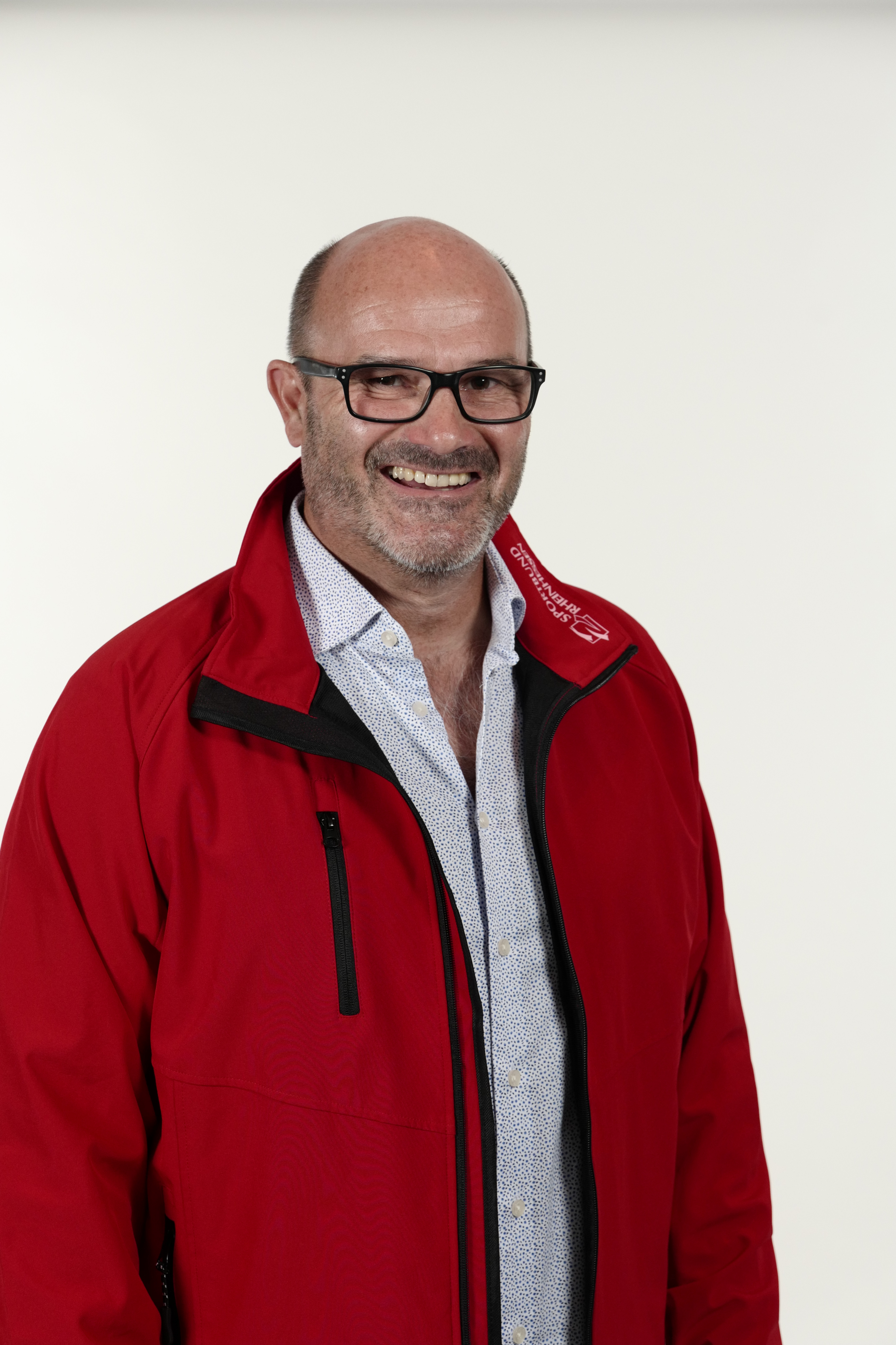Portrait von Rainald Kauer mit roter Jacke und Brille