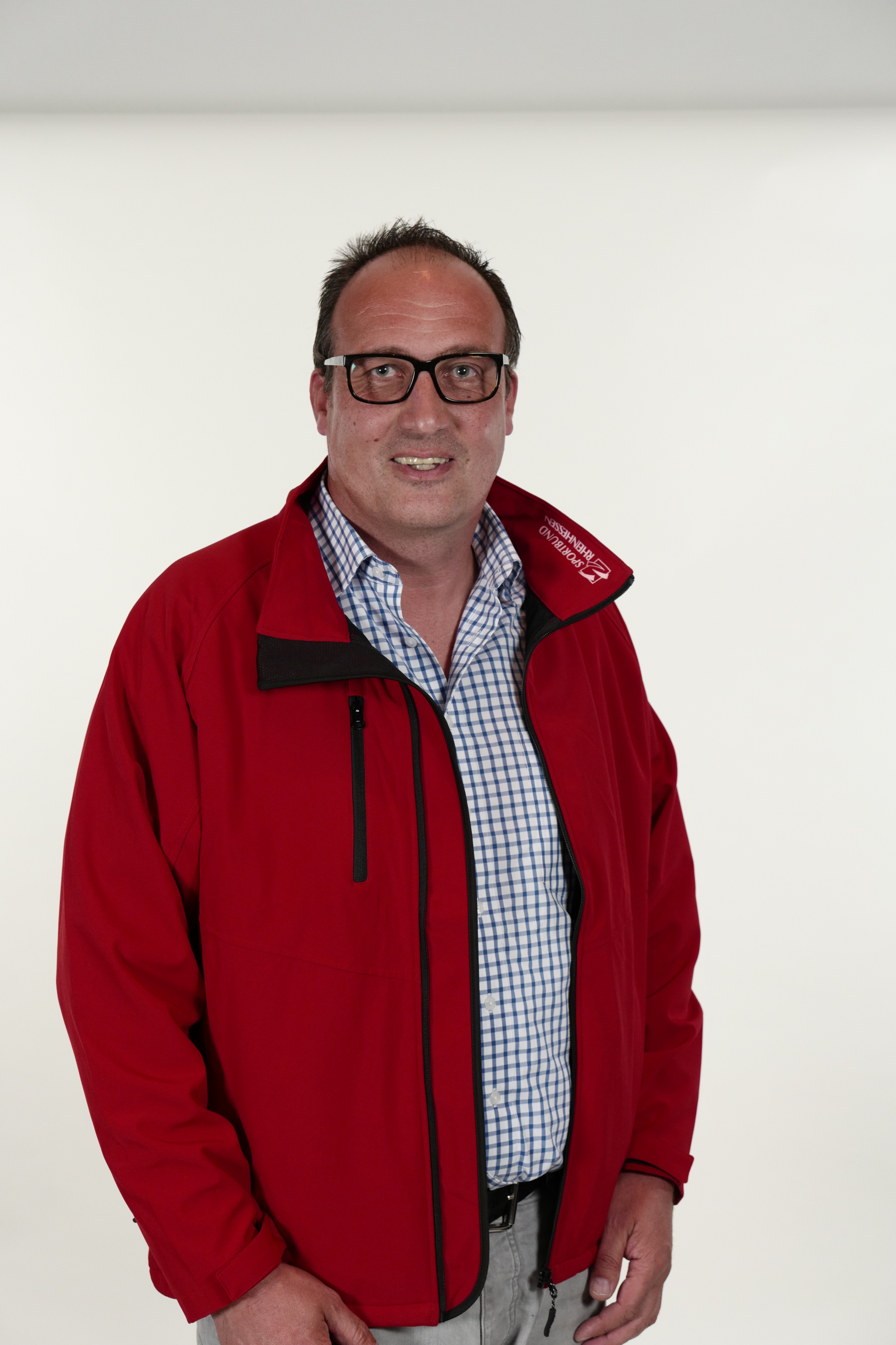 Frank Heilemann im Porträt mit roter Jacke vor hellem Hintergrund