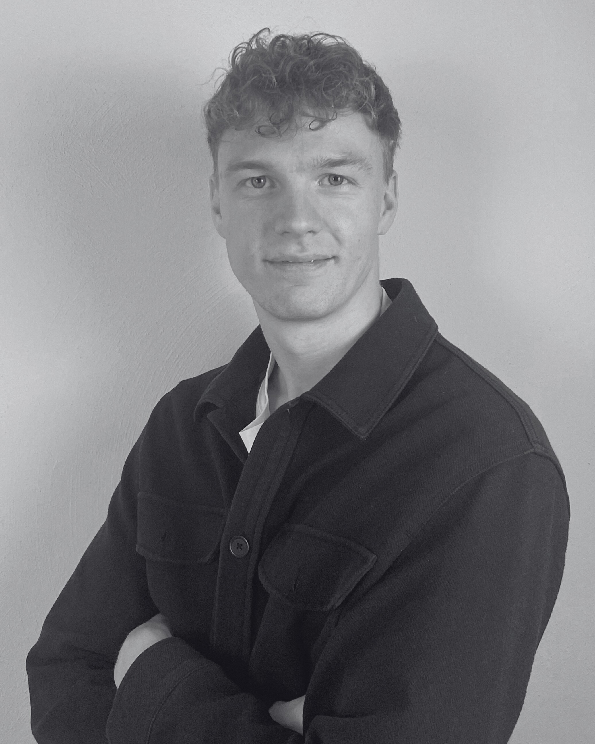 Porträt eines jungen Mannes in Schwarz-Weiß mit verschränkten Armen