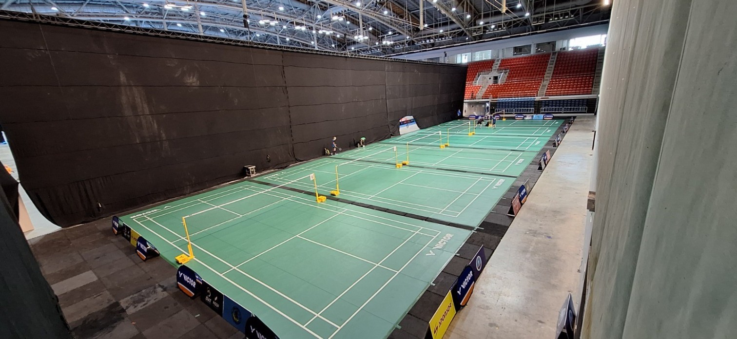 Leere Badmintonfelder in einer modernen Sporthalle mit Tribüne und Victor-Werbung