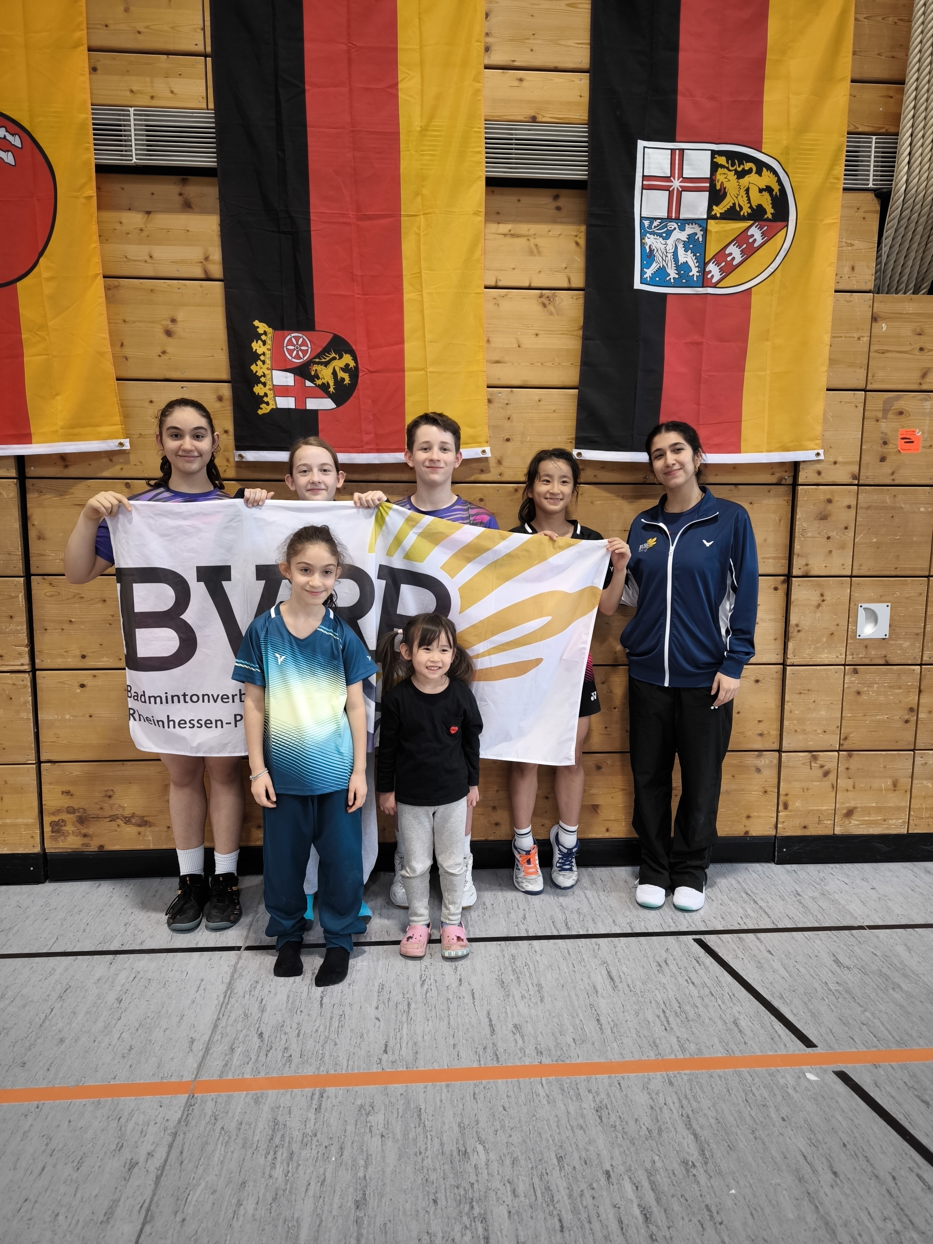 Gruppenfoto von U13 Badmintonspielerinnen und -spielern des BVRRP bei der Deutschen Meisterschaft vor Landesflaggen