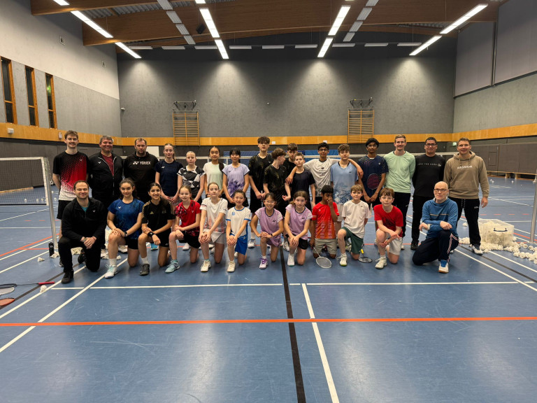 Gruppenfoto von Jugendlichen und Trainern in einer Badmintonhalle, Sportgruppe auf dem Spielfeld