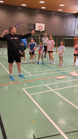 Trainer Lennart gibt Badminton-Unterricht für Kinder in einer Sporthalle