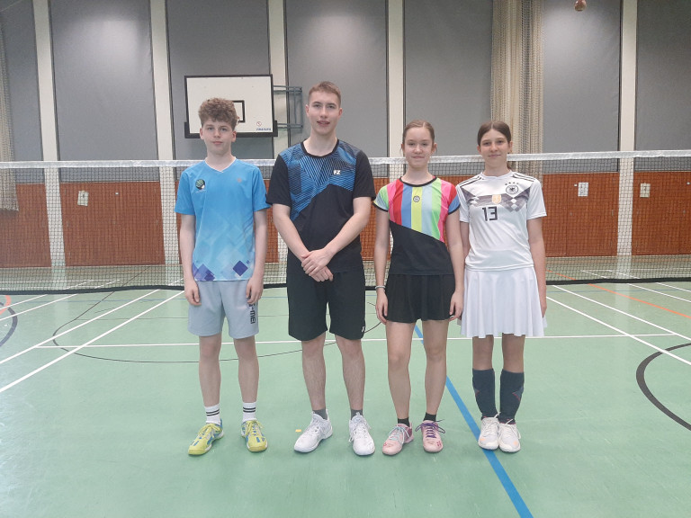 Vier Jugendliche in Sportkleidung stehen in einer Turnhalle vor einem Badmintonnetz, aufgenommen am 12.04.2026.