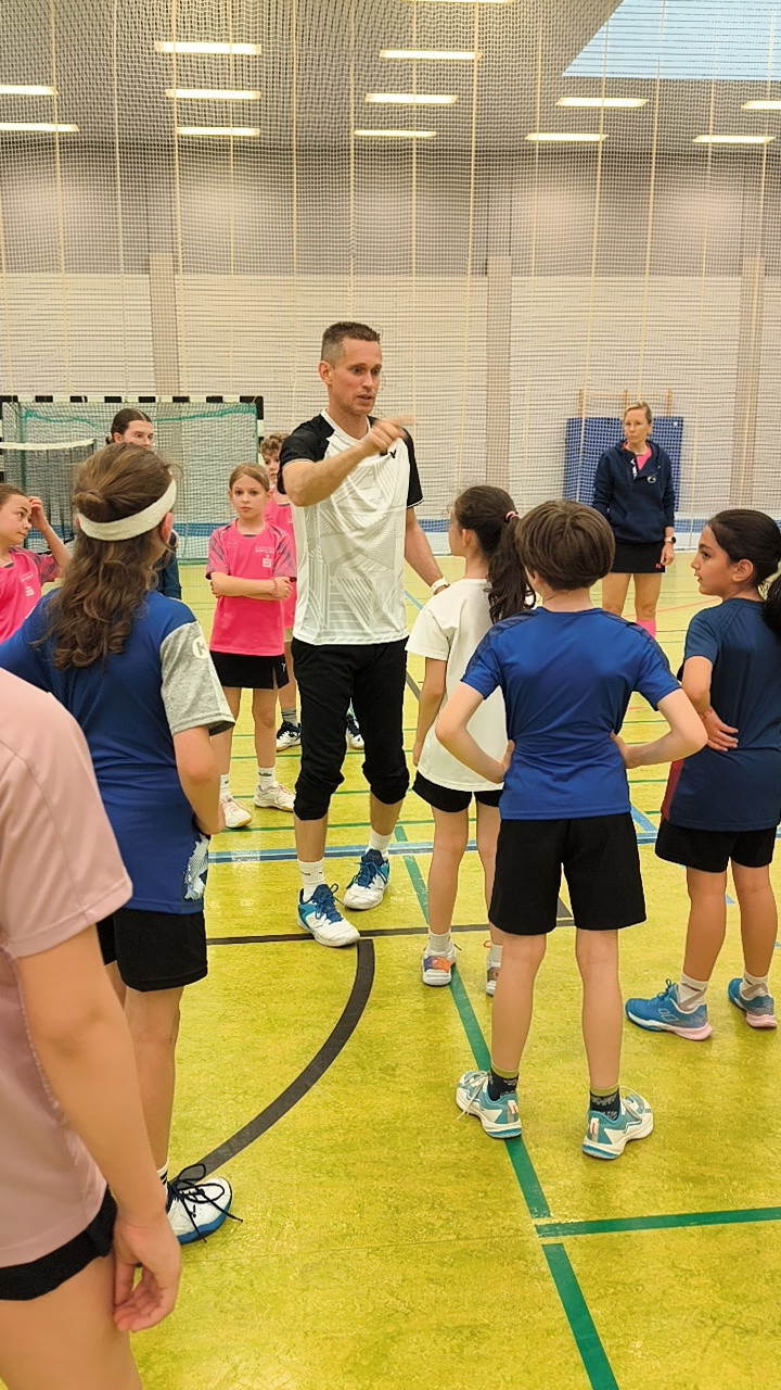 Trainer gibt Kindern Anweisungen beim Sportunterricht in einer Turnhalle