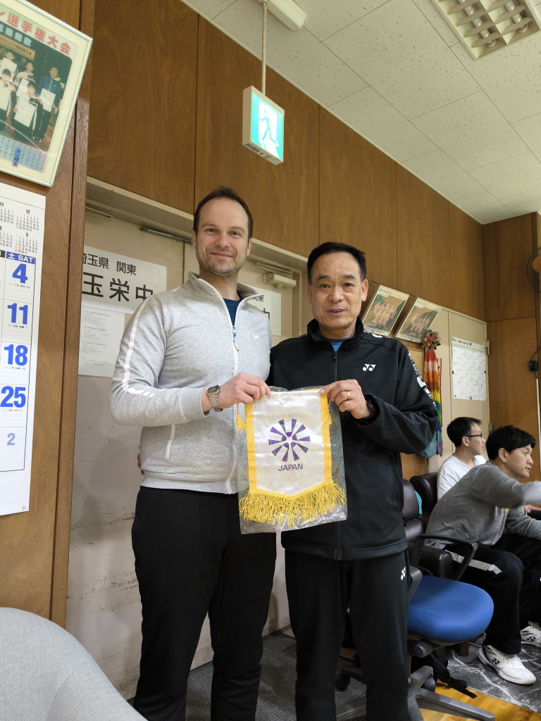 Zwei Männer halten einen Wimpel mit Japan-Emblem in einem japanischen Vereinsraum