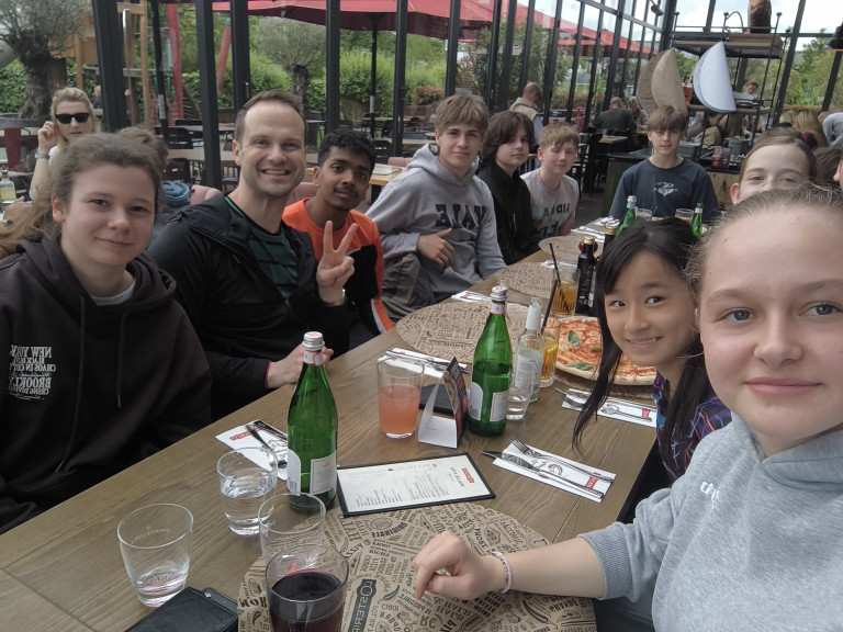 Gruppe von Jugendlichen beim gemeinsamen Essen in einem Restaurant, Getränke und Pizza auf dem Tisch