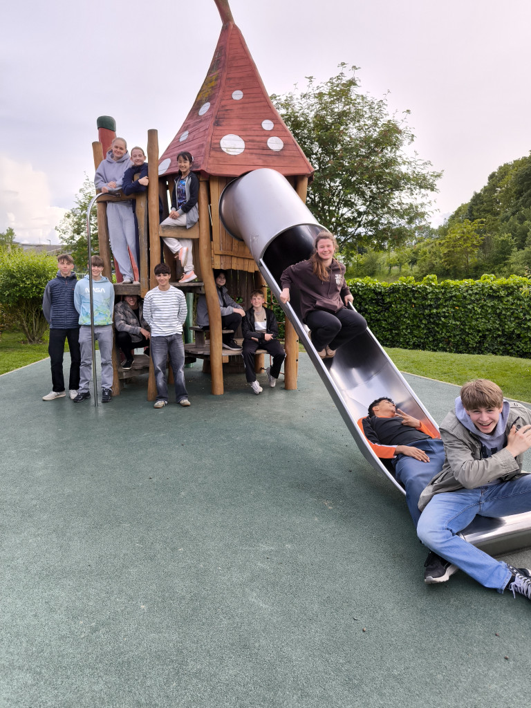 Gruppe von Jugendlichen auf einem Spielplatz mit Holzspielhaus und Rutsche