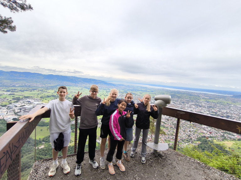 Gruppe von Jugendlichen auf einer Aussichtsplattform mit weitem Blick über eine Stadt und Landschaft