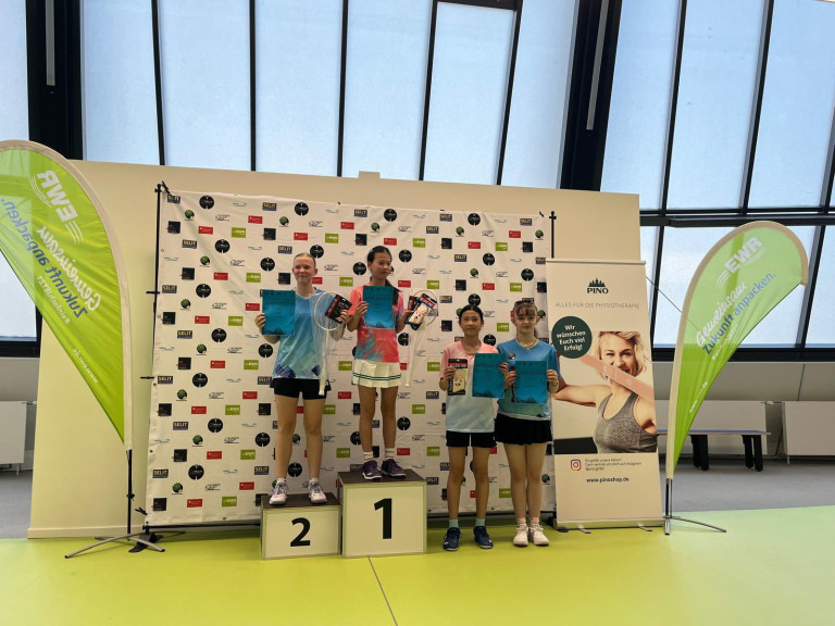 Siegerehrung Badminton-Turnier – vier Spielerinnen mit Urkunden und Preisen auf dem Podium Siegerehrung bei einem Badminton-Turnier mit vier jungen Spielerinnen auf dem Podium, die Urkunden und Preise halten.