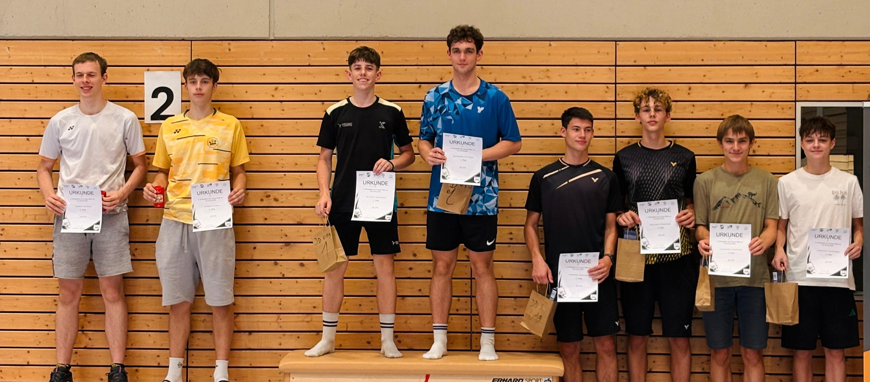 Siegerpodest mit drei jungen Badmintonspielern, die Urkunden und Geschenke halten