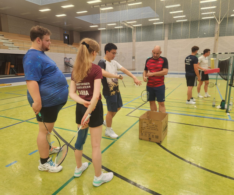 Teilnehmer beim Hobby-Breitensportcamp spielen Badminton in einer Sporthalle