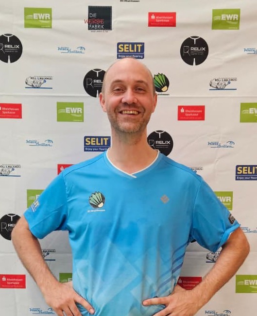 Daniel Wagner im blauen Sporttrikot vor Sponsorenwand beim Sportevent