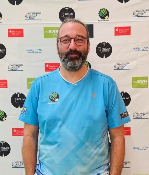 Michael Bothner im Trikot des SG Rheinhessen Badmintonvereins vor Sponsorenwand