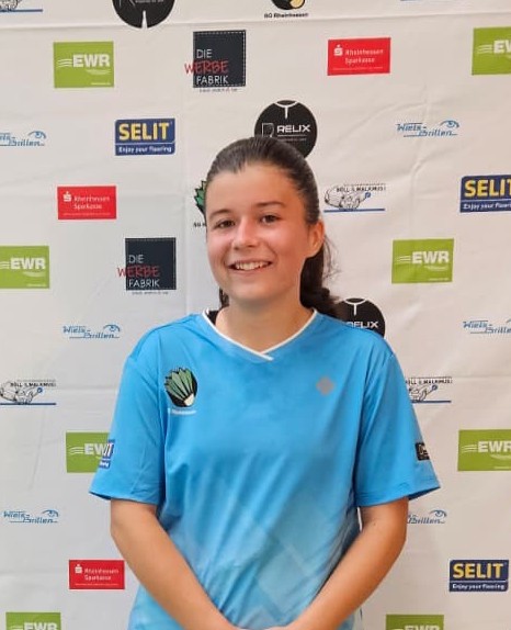 Emilia Winkler im blauen Trikot vor Sponsorenwand