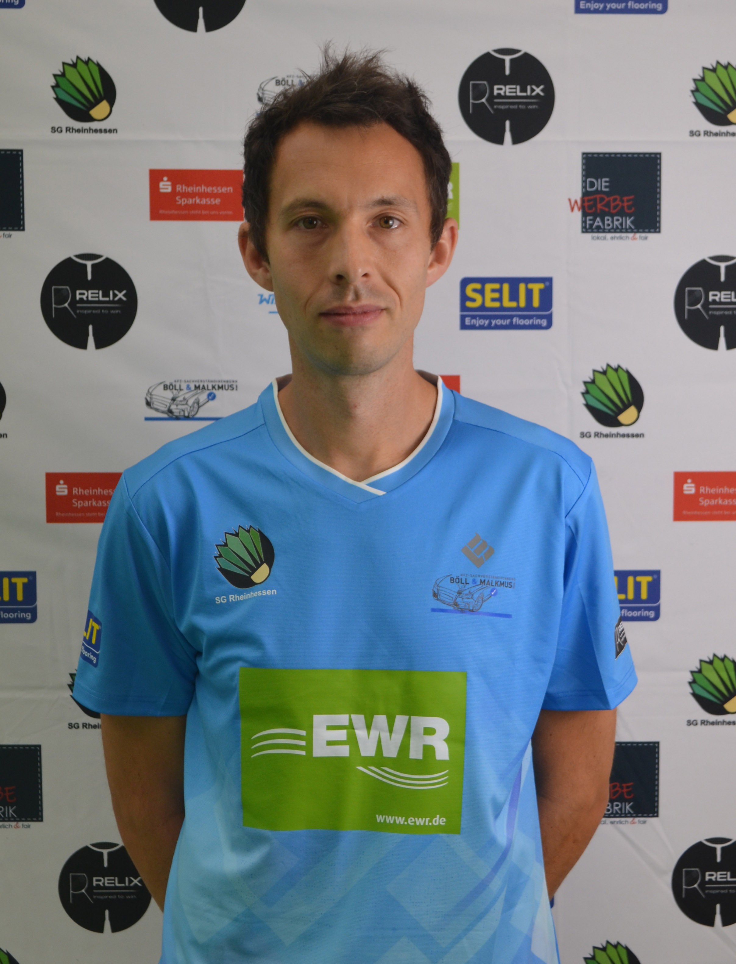 Spieler der SG Rheinhessen im Trikot mit EWR-Logo vor Sponsorenwand