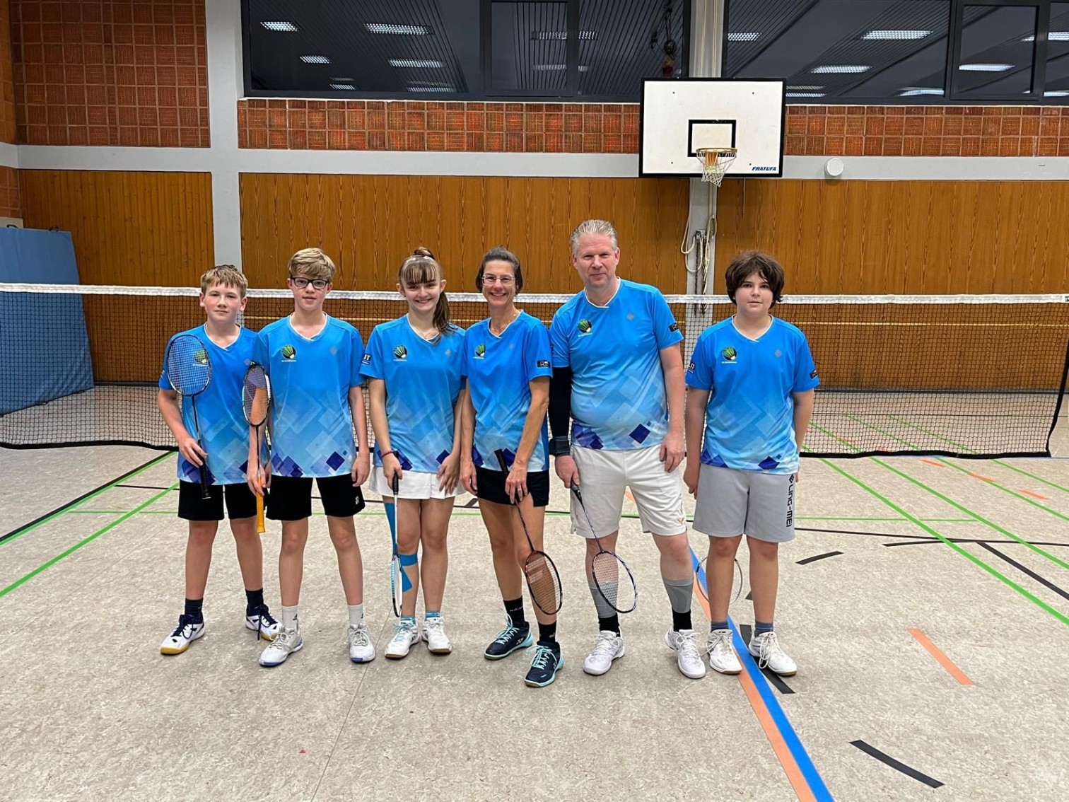 Badminton-Team in blauen Trikots in einer Sporthalle mit Badminton-Schlägern