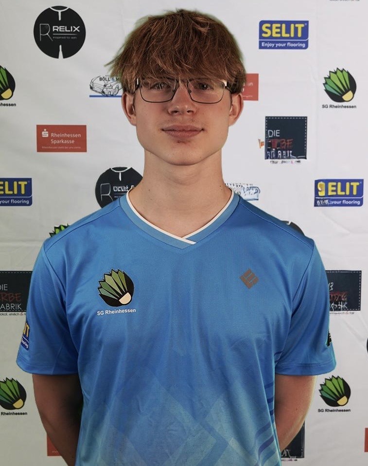 Spieler im blauen Trikot der SG Rheinhessen vor Sponsorenwand