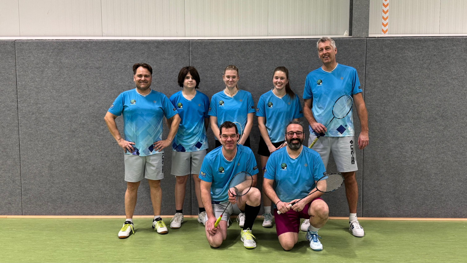 Badminton Mannschaftsfoto in blauen Trikots in der Sporthalle