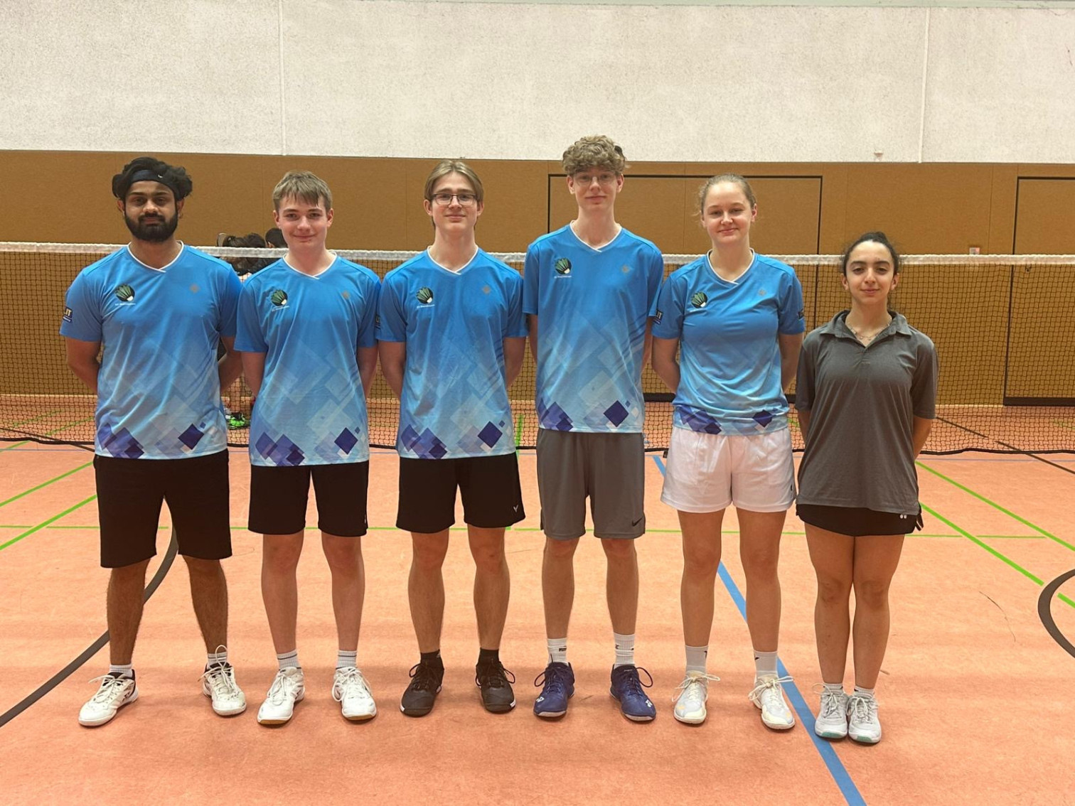 Badminton Mannschaft in blauen Trikots in Sporthalle