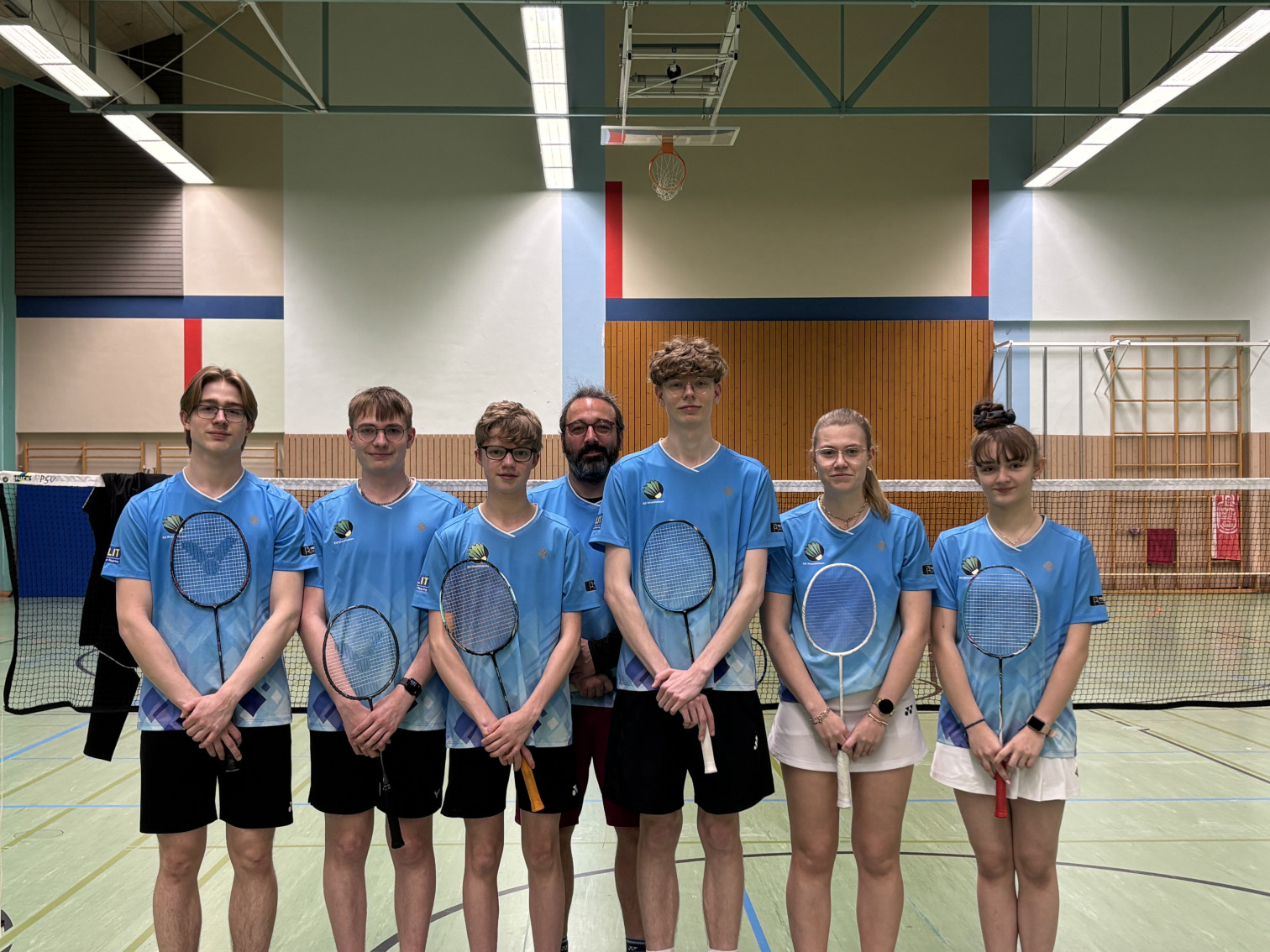 Badminton Mannschaft in blauen Trikots in einer Sporthalle