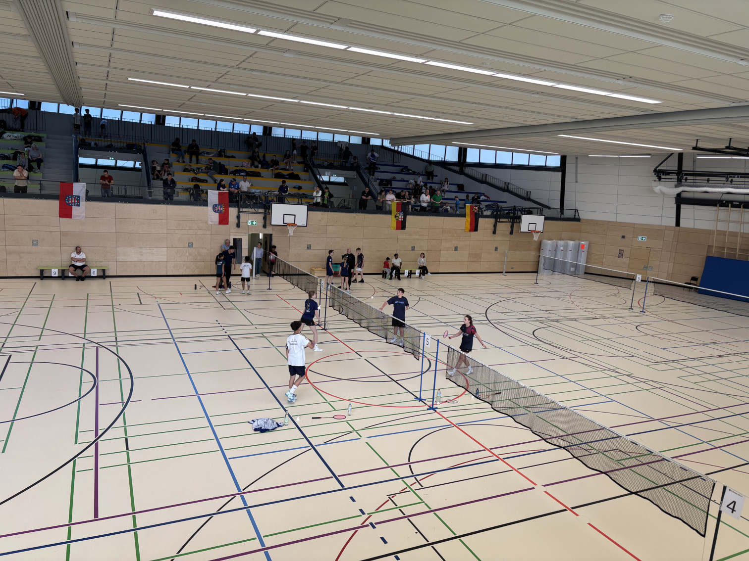 Badminton-Turnier in moderner Sporthalle mit Zuschauern auf der Tribüne