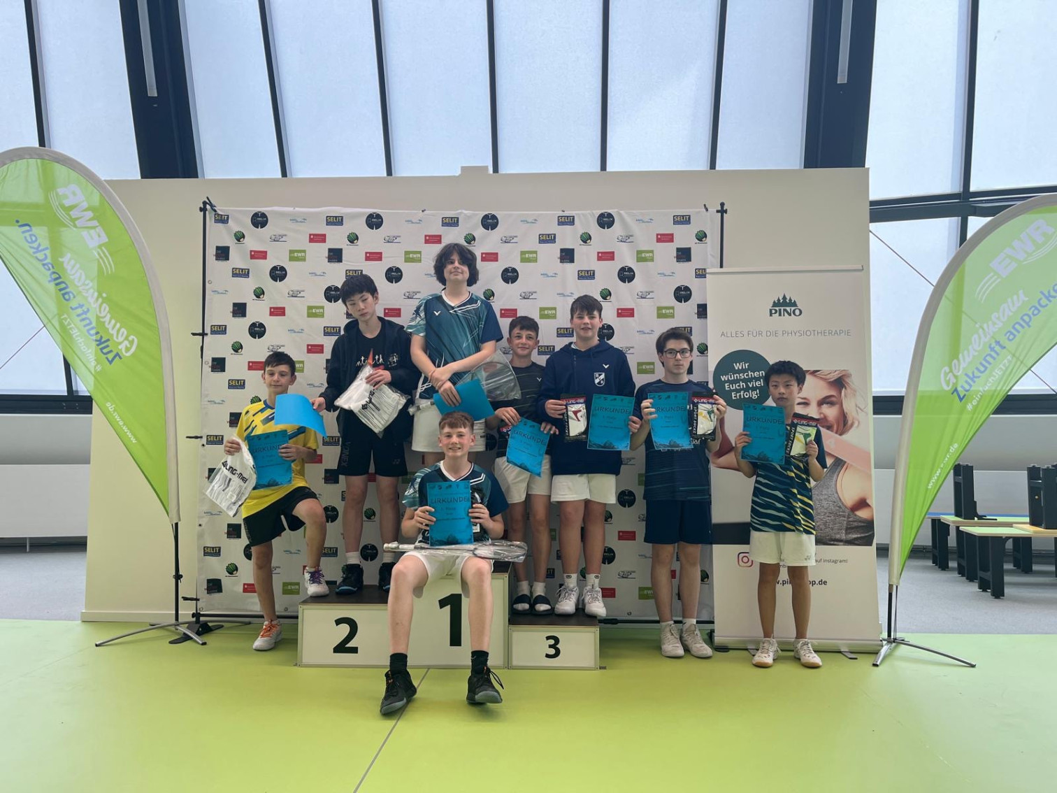 Jugendliche bei einer Siegerehrung in einer Sporthalle mit Urkunden und Preisen