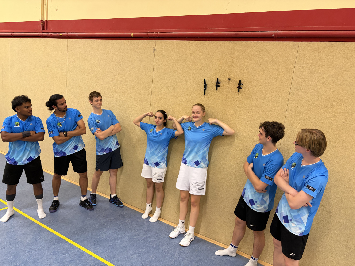 Junge Sportlerinnen und Sportler in blauen Trikots stehen in einer Sporthalle an der Wand und posieren gemeinsam