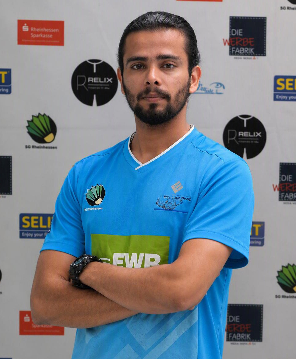 Ajay im blauen Trikot der SG Rheinhessen vor Sponsorenwand