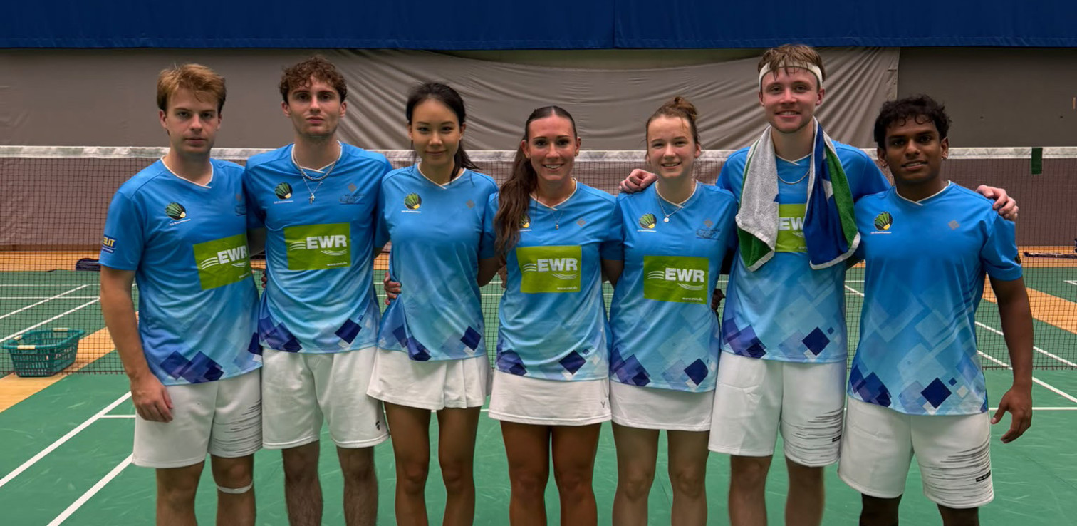 Gruppenfoto eines Badminton-Teams in blauen Trikots mit EWR-Logo vor einem Badminton-Netz, aufgenommen am 4. Oktober 2026