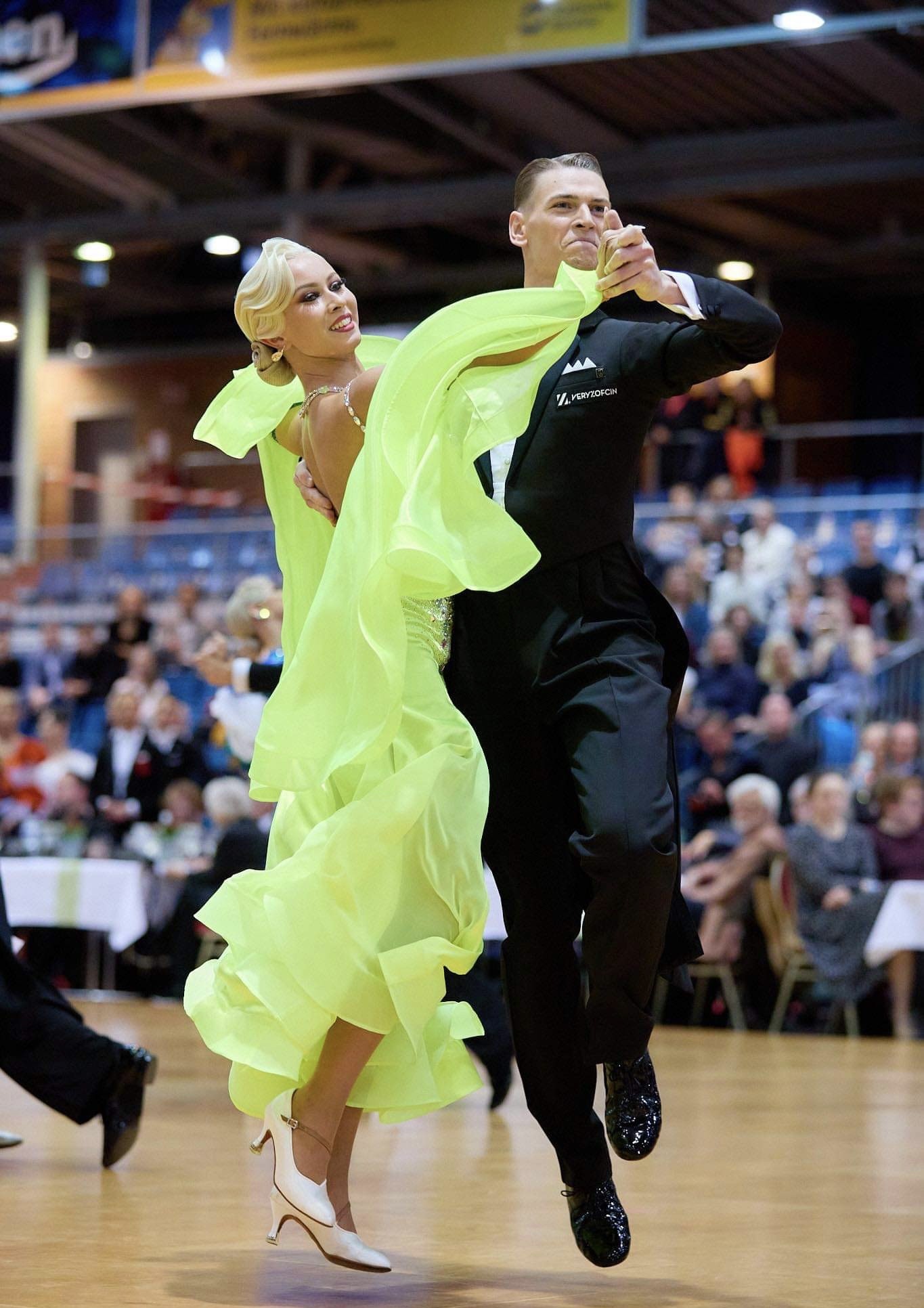 Elegantes Tanzpaar in lebhaftem Tanzkleid bei einem Tanzturnier