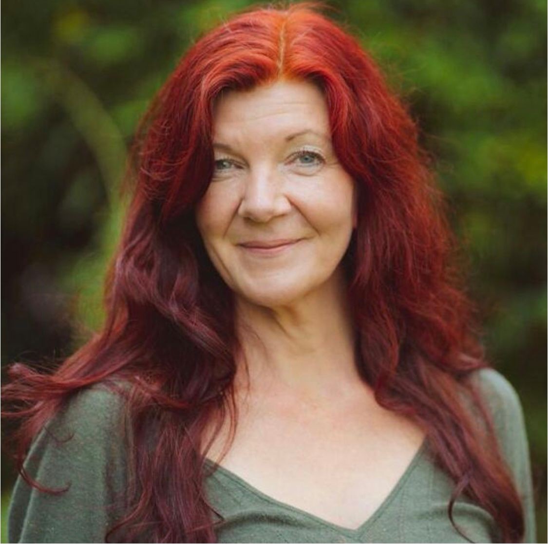 Porträt einer lächelnden Frau mit langem, rotem Haar im Freien