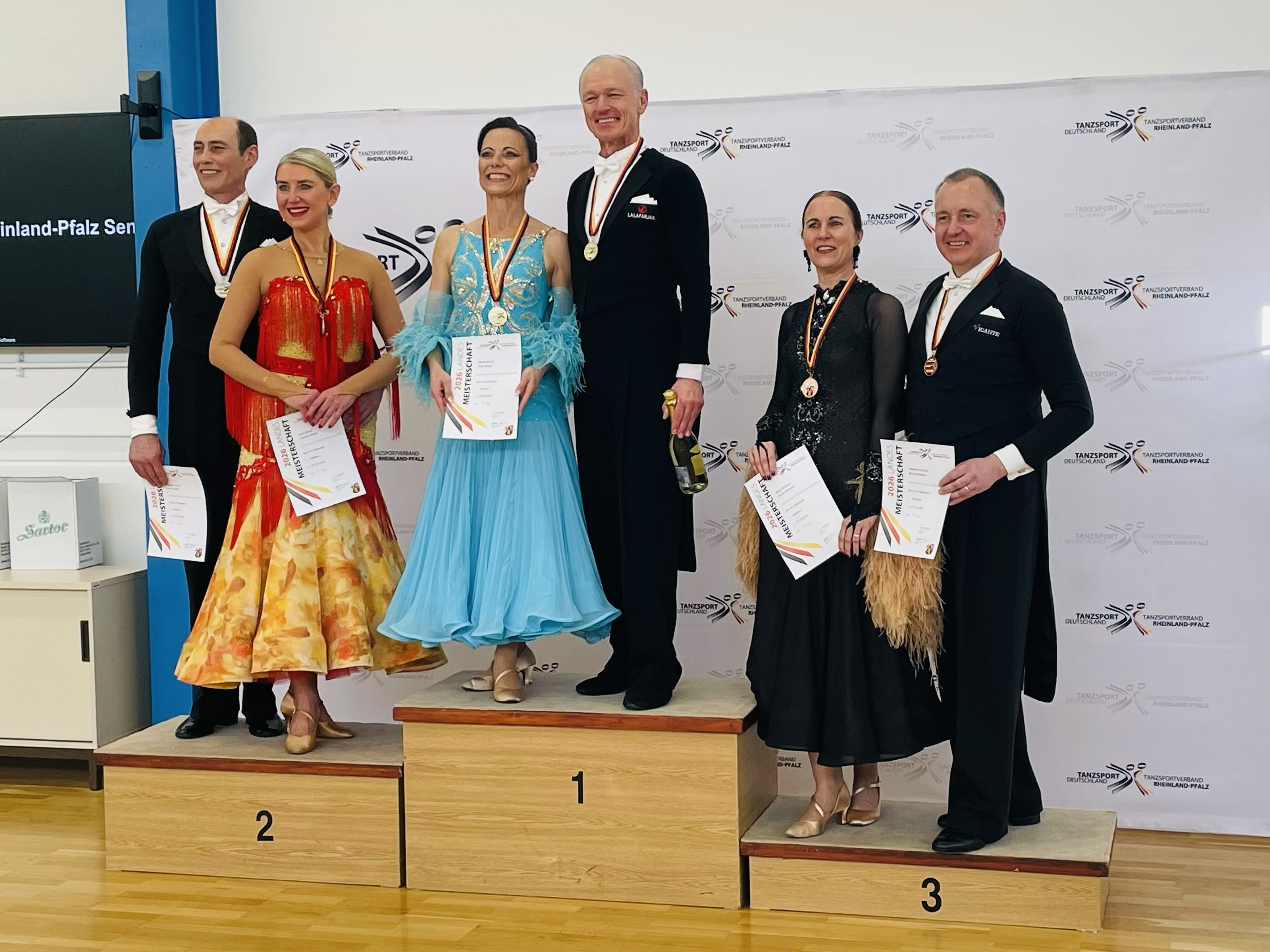 Siegerehrung eines Tanzturniers mit Paaren auf dem Podest und Urkunden, Tanzsportverband Rheinland-Pfalz