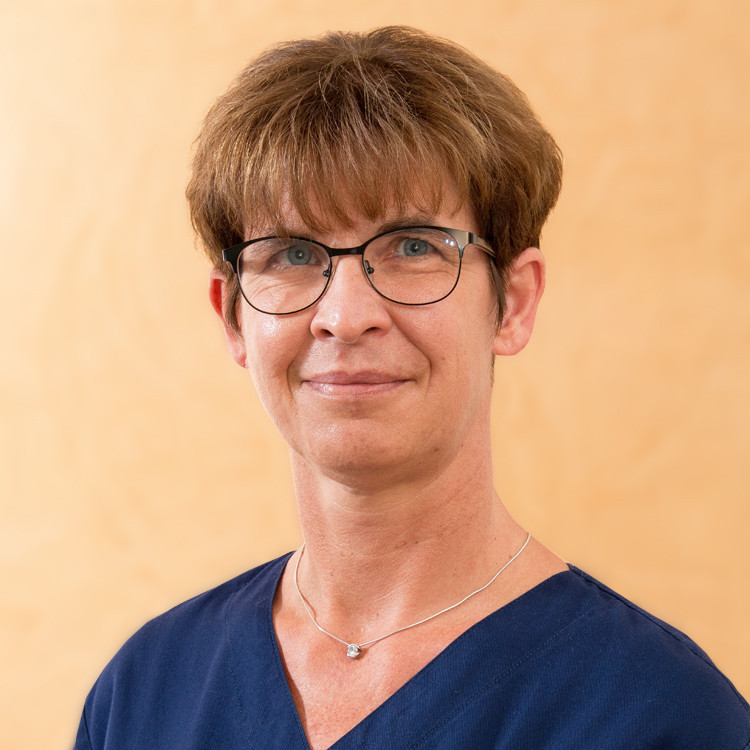 Portrait von Marita Specht in medizinischer Berufskleidung vor hellem Hintergrund