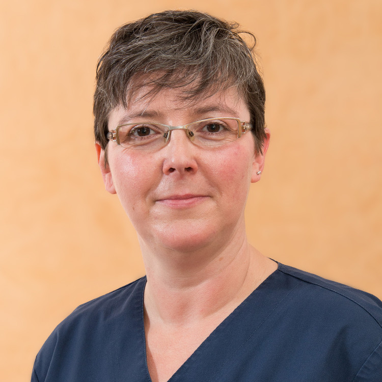 Portrait von Sandy Gaunitz in medizinischer Kleidung vor neutralem Hintergrund