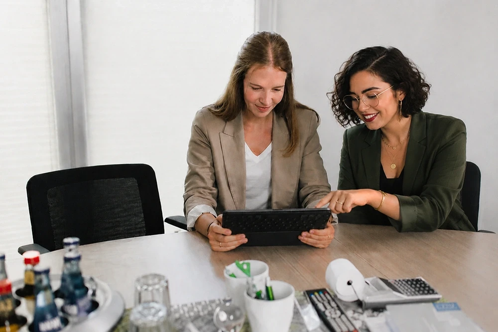 Zwei Mitarbeiterinnen schauen gemeinsam auf ein Tablet im Büro