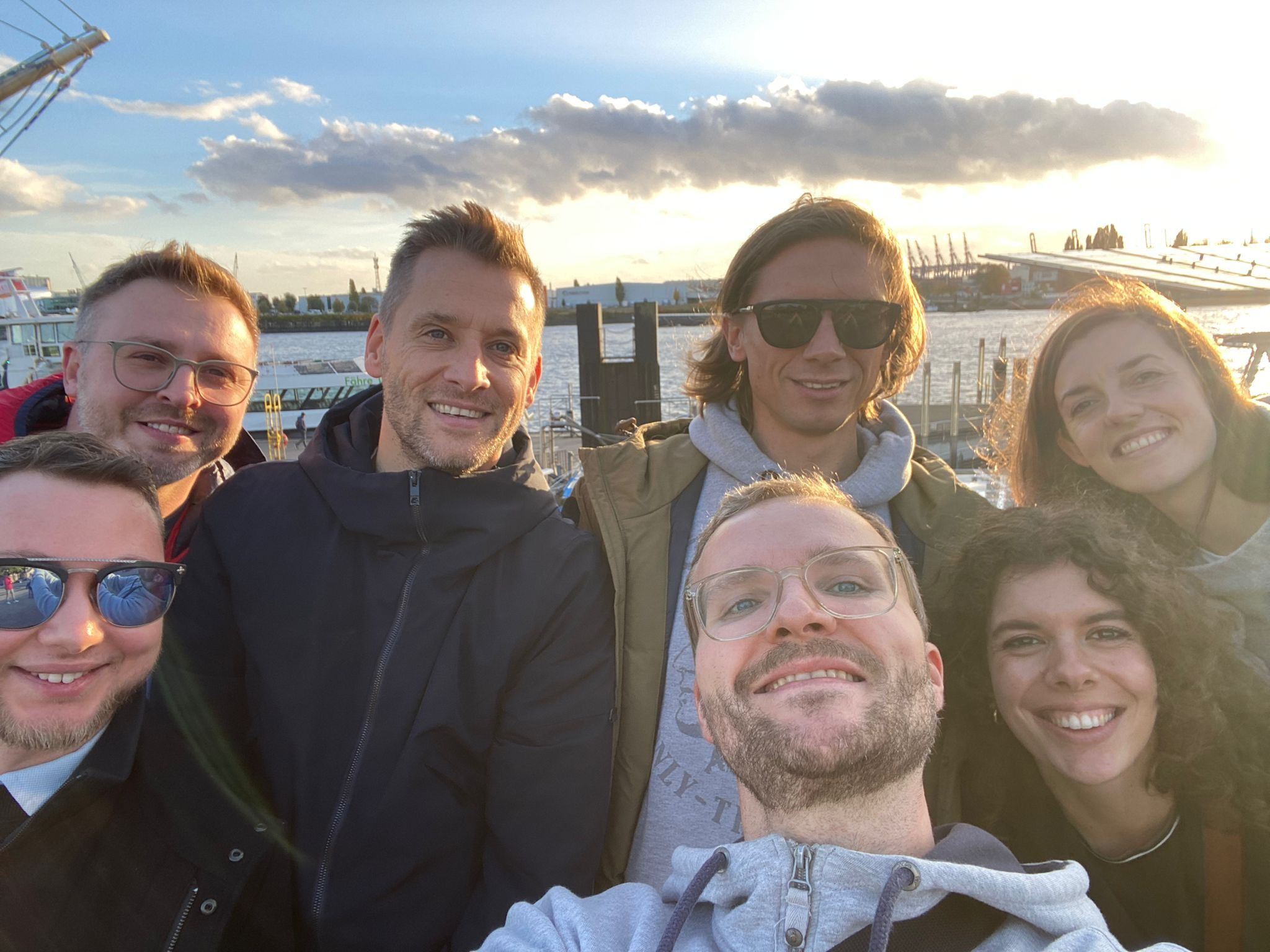 Gruppe von Freunden am Flussufer bei Sonnenuntergang