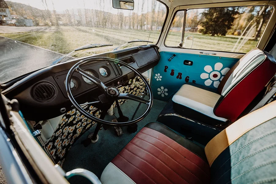Innenraum eines nostalgischen Wagens mit bunten Sitzen und Blumenmustern