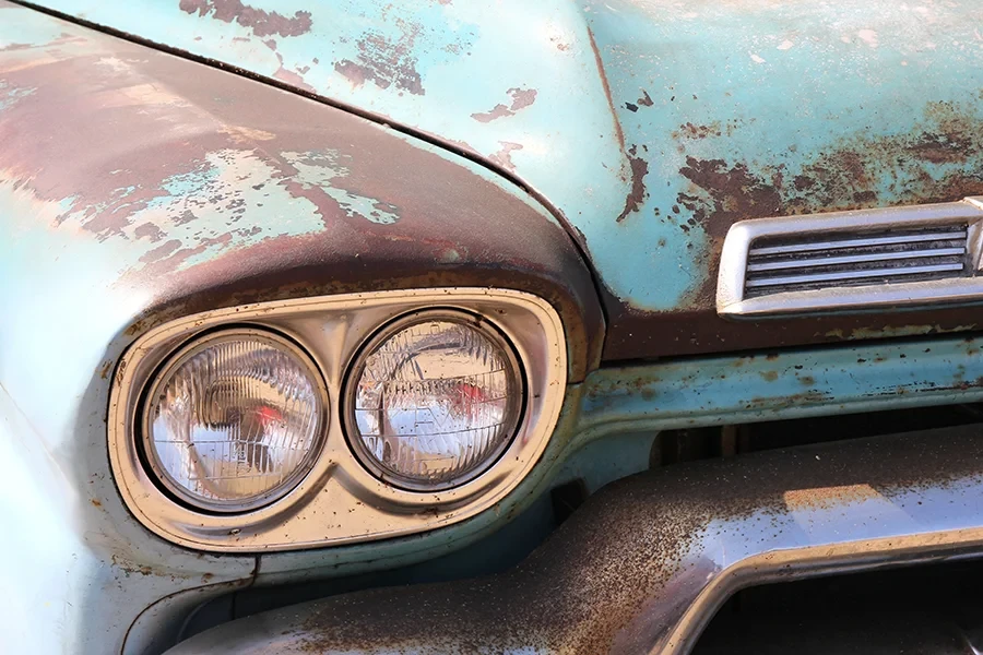 Nahaufnahme eines alten, rostigen Oldtimers mit blauer Lackierung und Doppelscheinwerfern