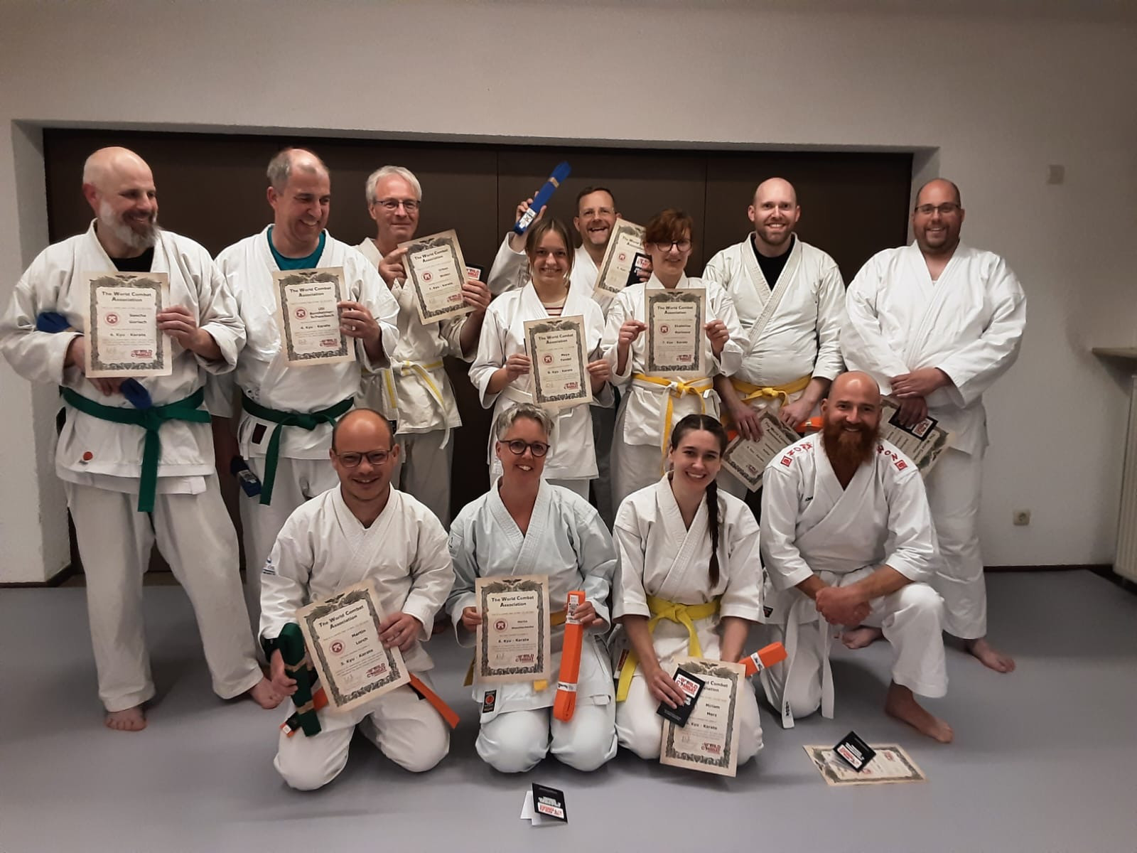 Gruppenfoto von Karateka nach bestandener Gürtelprüfung mit Urkunden und neuen Gürteln