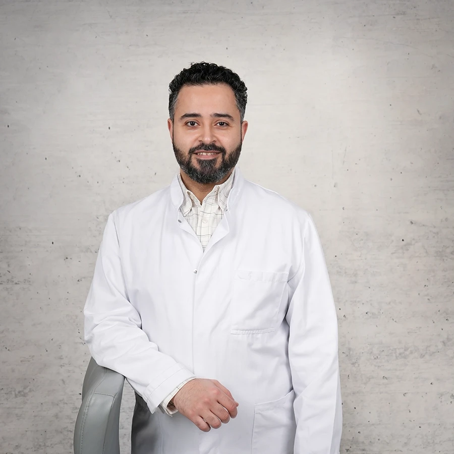 Ahmad Issa im weißen Arztkittel vor grauem Hintergrund