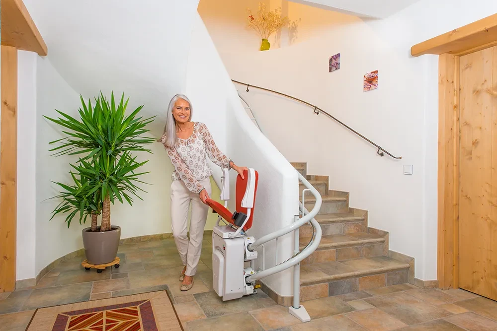 Treppenlift Alpha Classic fr kurvige Treppen im Einsatz mit Frau