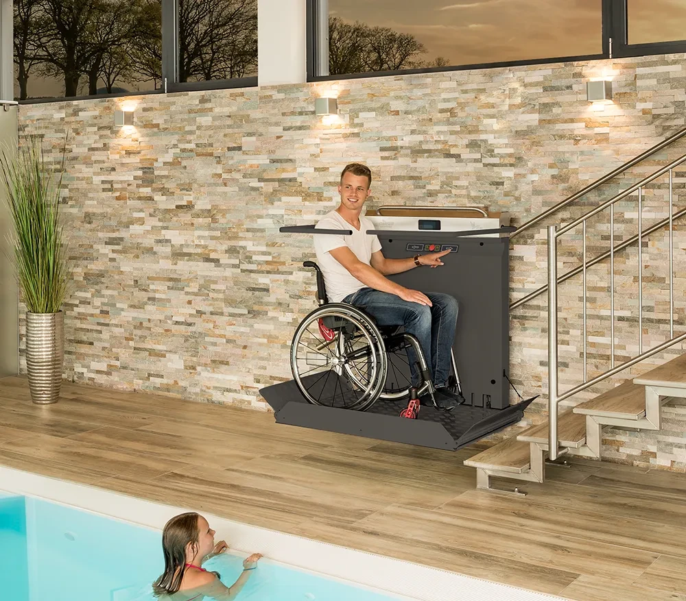 Mann im Rollstuhl nutzt Ganser Plattformlift an Treppe im Schwimmbad