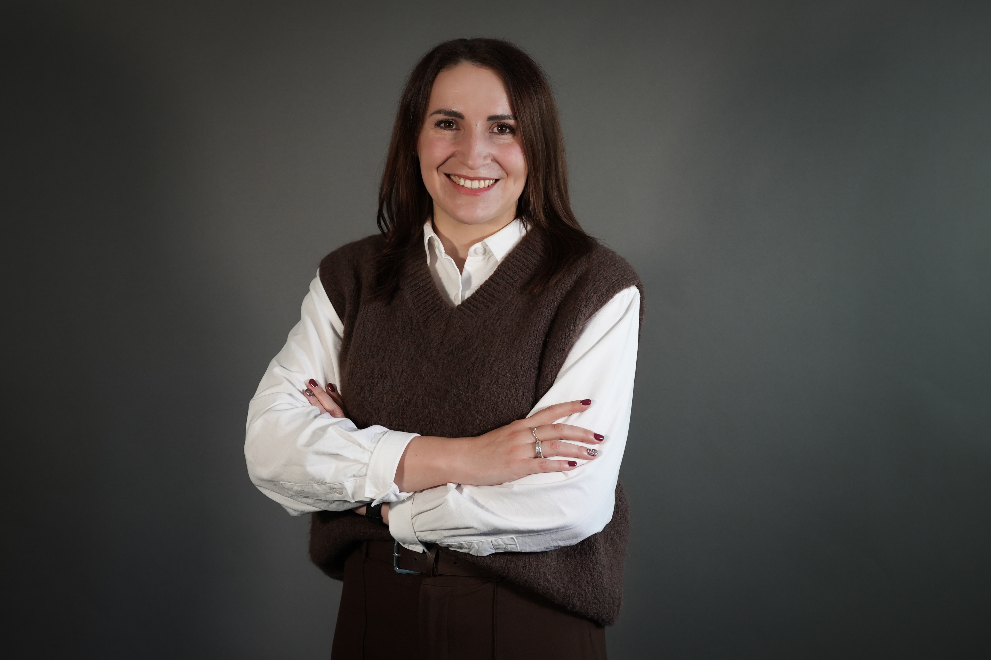 Jennifer Karpinski mit verschränkten Armen vor grauem Hintergrund