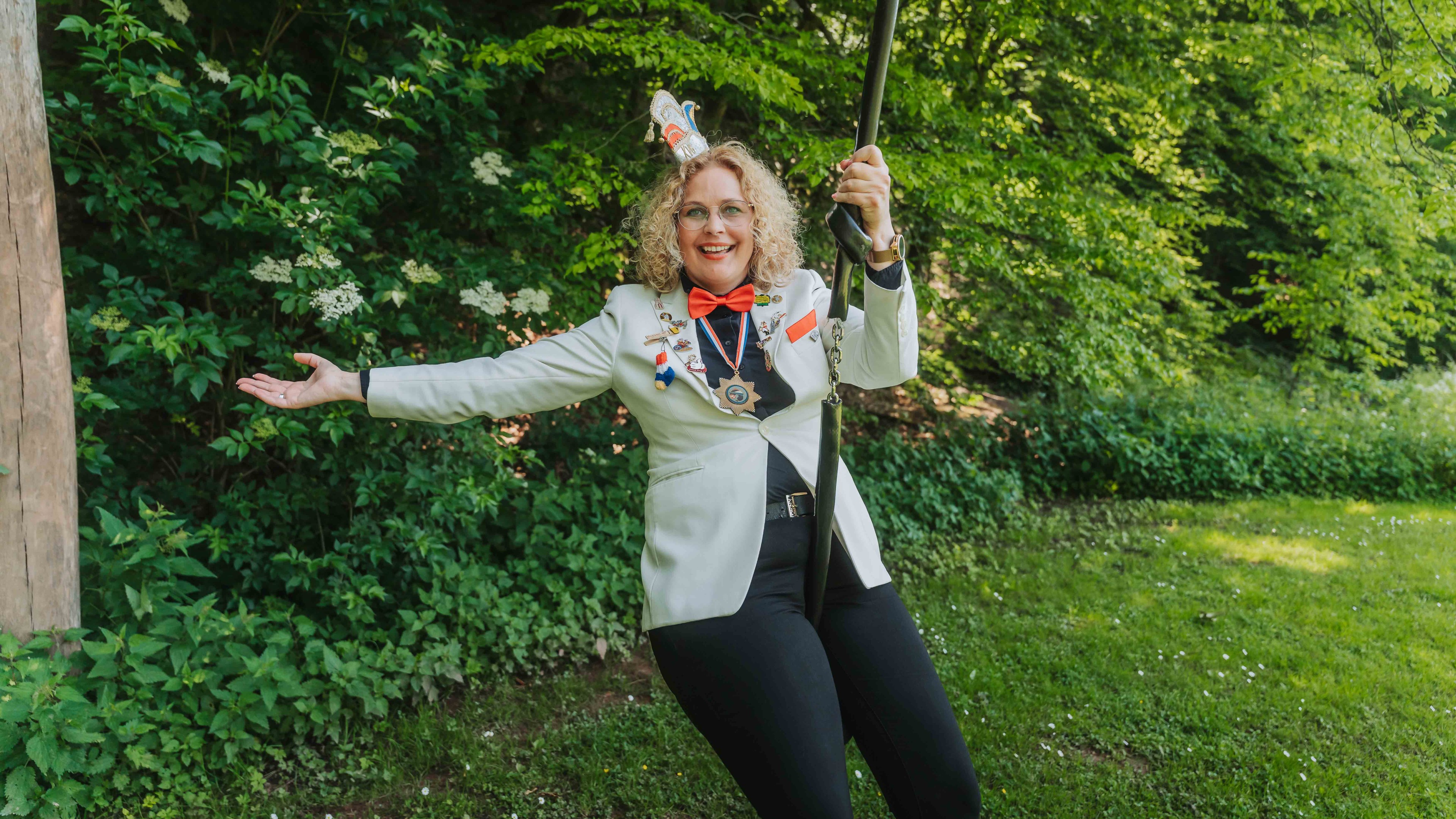 Person mit festlicher Kleidung, Medaillen und roter Fliege bei einer Schützenveranstaltung im Grünen – alea alternativ s 031