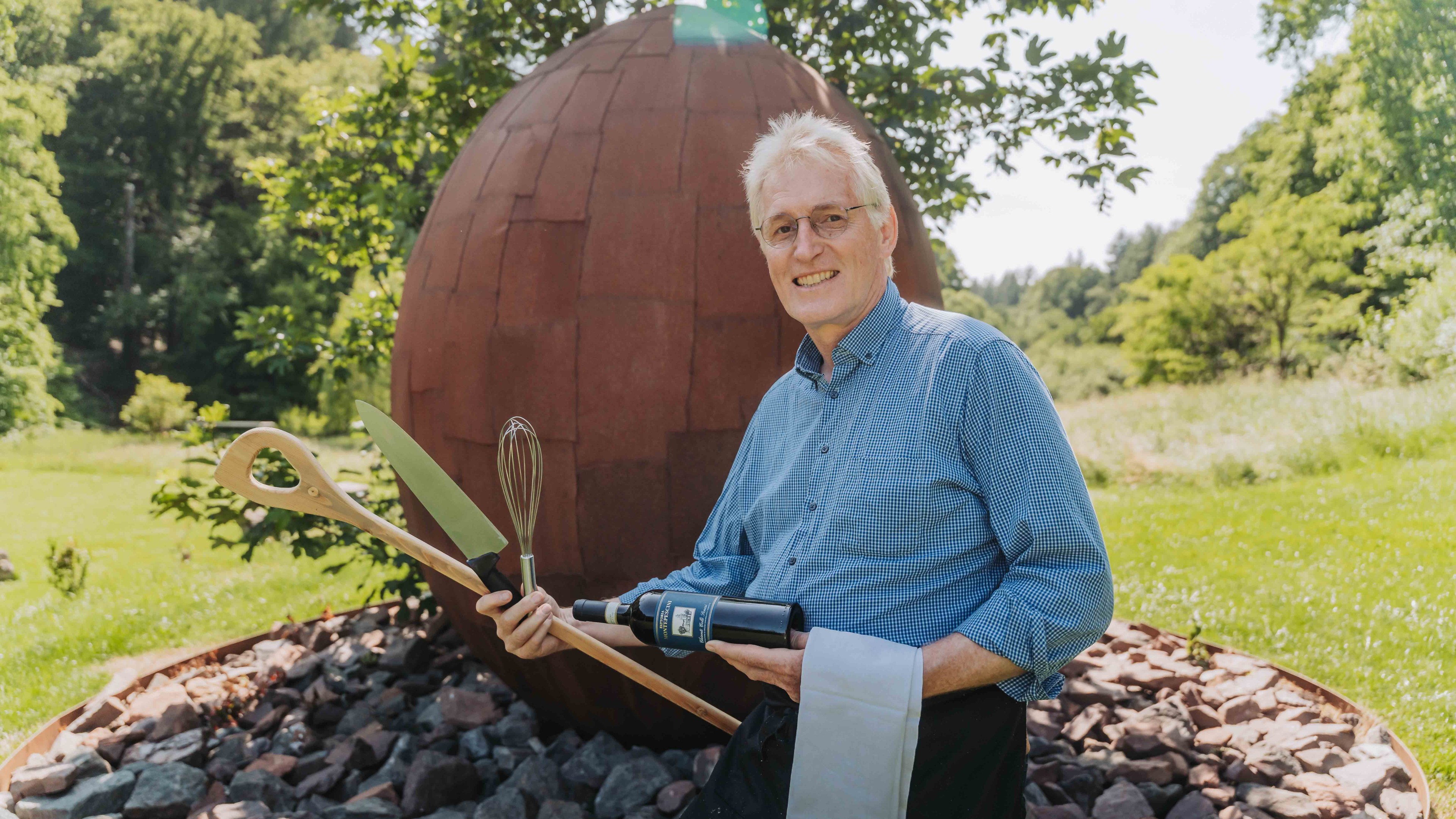 Person mit Kochutensilien vor einer großen Skulptur im Freien – alea alternativ s 19